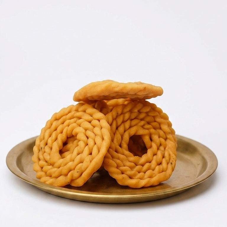 Five pieces of Kai Murukku, a crunchy Indian snack by Kaipunnyam, arranged in four lines on a plate.